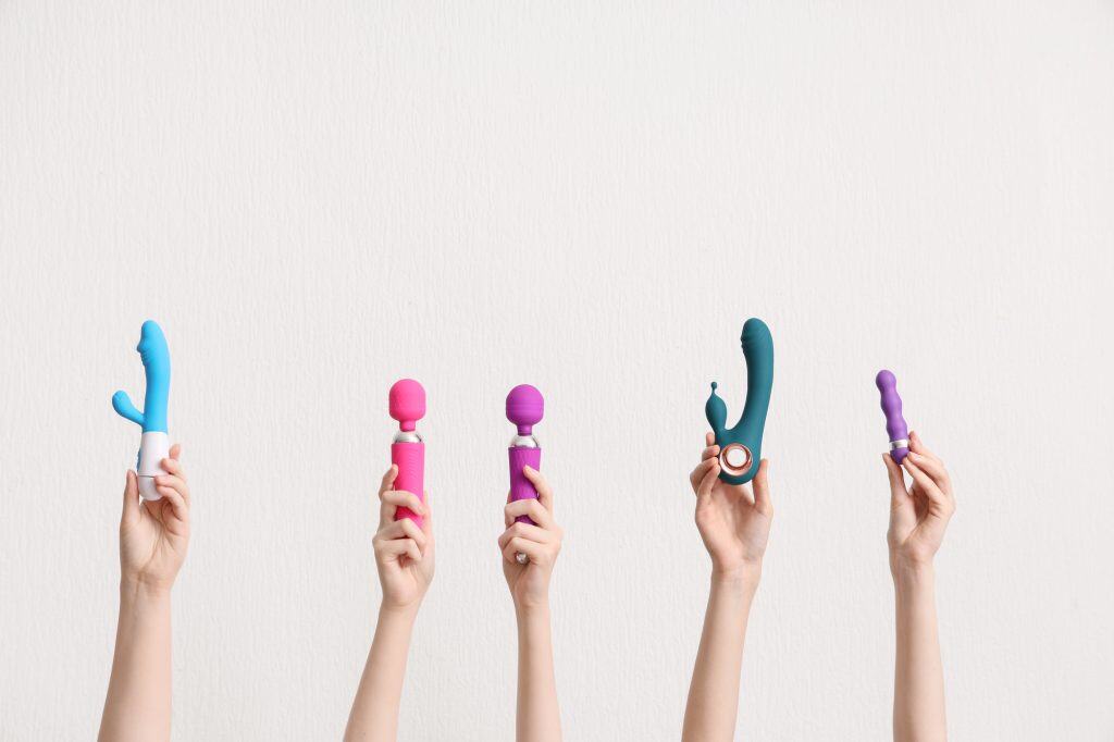 Best Vibrators for Hotwife Play. Five hands holding different types of best vibrators for hotwife play and personal massagers against a plain white background.